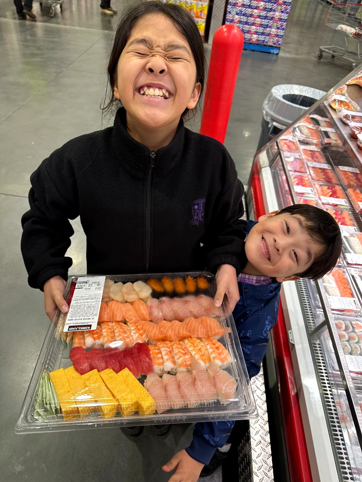 Costcoで買った寿司の大きなトレイを持つ子どもたち